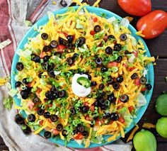 a salad with black olives, cheese and lettuce on a blue plate