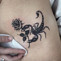 a woman's stomach with a scorpion and roses tattoo on it, next to a computer mouse