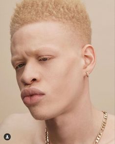 a man with blonde hair wearing a gold chain necklace and earring on his neck