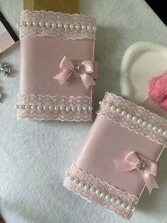 two pink wedding guest book covers with pearls and bows on the edges, sitting on a table