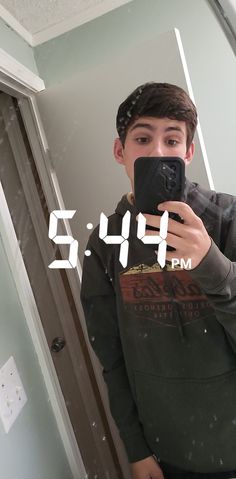 a young man taking a selfie in front of a mirror with the clock on it