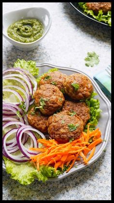 a plate with meatballs, carrots and lettuce next to a bowl of guacamole