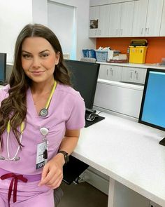 a woman in scrubs sitting at a desk