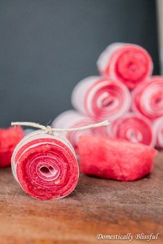 two rolled up pieces of fruit sitting next to each other on a wooden table with text overlay that reads watermelon fruit leather recipe only 2 ingredients