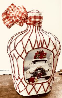 an old fashioned glass bottle with a bow on it's head is adorned with red and white plaid ribbon