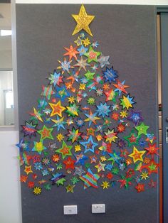 a christmas tree made out of colorful paper stars on a gray wall in an office