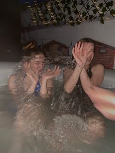 two women in a hot tub with their hands up