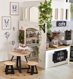 a small child's play kitchen and table in a room with pictures on the wall