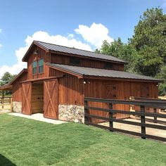 a barn with a horse pen in front of it and grass around the yard area