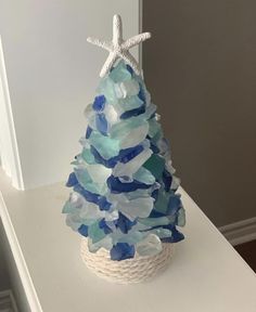 a blue and white christmas tree made out of sea glass with a starfish on top