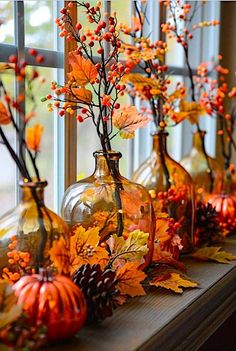 some vases filled with leaves and flowers on a window sill