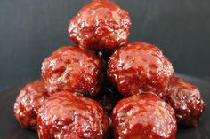 a pile of meatballs covered in ketchup on top of a black plate