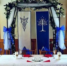 a table set up for a wedding with blue sashes and white flowers on it