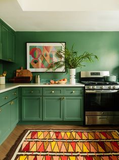 a kitchen with green cabinets and an area rug on the floor in front of the stove