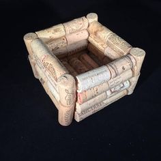 a small chair made out of wine corks on a black surface with the seat up