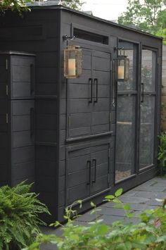 a black outhouse sitting in the middle of a garden