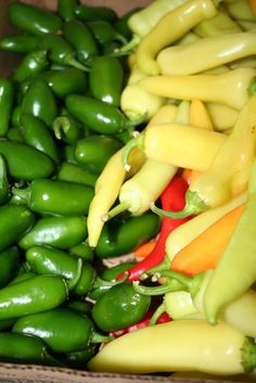 several different types of peppers in a box together on the table, including green beans and yellow bell peppers