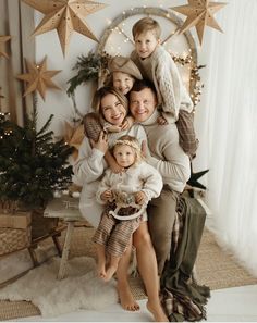 a family posing for a christmas photo in front of a star - decorated wall and tree