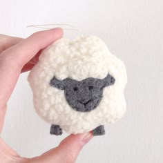 a hand is holding a small sheep ornament