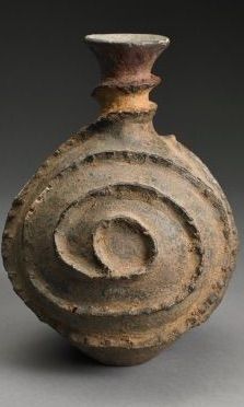 an old pottery vase with spiral designs on the outside and inside, sitting on a gray surface