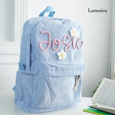 a blue backpack sitting on top of a table next to an open book and pen