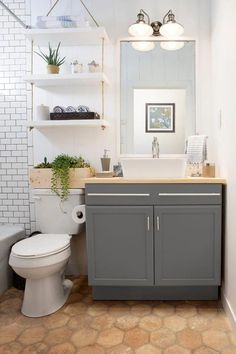 a white toilet sitting next to a sink in a bathroom under a mirror and lights