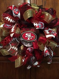 the san francisco giants football wreath is on display in front of a wooden door with red, gold and white ribbons