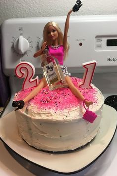 a barbie doll sitting on top of a birthday cake with pink sprinkles