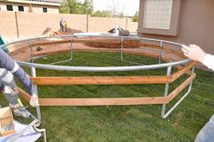 two men are working on an inflatable pool that is being built into the grass