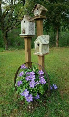 two bird houses and some purple flowers in the grass