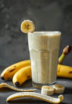 a banana sitting on top of a table next to two bananas and a glass with something in it