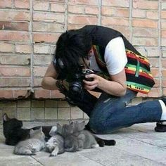 a man taking a photo with his camera while two cats lay on the ground next to him