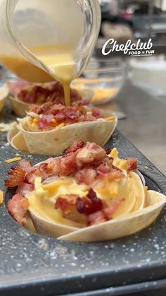 some food is being poured into small cups on a tray with other dishes in the background