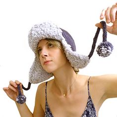 a woman wearing a hat and holding a string to her ear with two balls on it