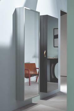 an open mirrored door in the middle of a room next to a chair and table