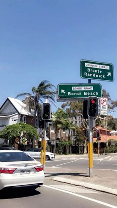 two street signs on the side of a road next to a traffic light and parked cars