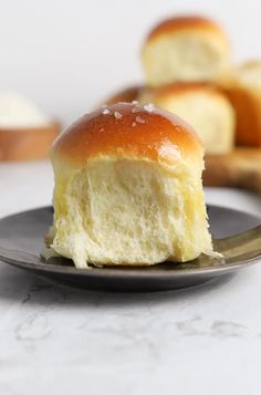 a close up of a bun on a plate with bread in the back ground behind it