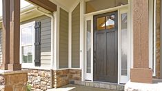 the front porch of a house with two doors and brick pillars on each side, along with stone steps leading up to it