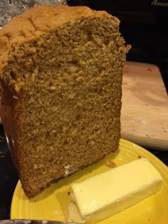 a loaf of bread sitting on top of a yellow plate next to a knife and butter