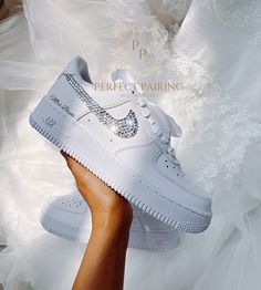 a person holding up a white nike air force shoe in front of a wedding dress