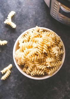 a white bowl filled with pasta next to an instant pressure cooker