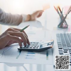 a person using a calculator on top of a desk next to a laptop