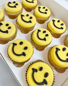 cupcakes with yellow frosting and black icing have smiley faces on them