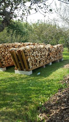 a large pile of wood sitting on top of a lush green field