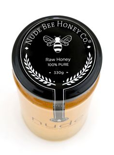 a jar of honey sits on a white surface with the label made bee honey co