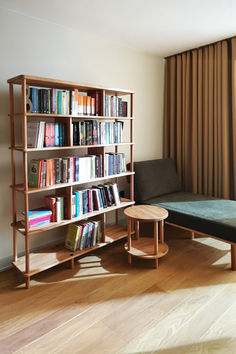 a living room filled with furniture and a book shelf next to a window covered in curtains