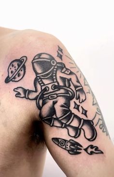 a man with a spaceman tattoo on his arm and shoulder, holding a rocket ship