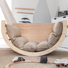 a child's bedroom with toys on the floor and a wooden swing chair in the middle