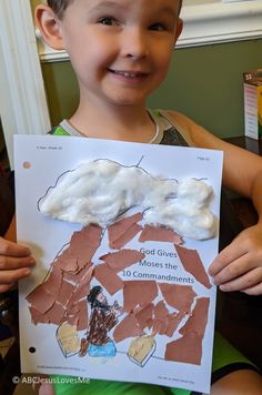 a young boy is holding up a paper cut out of clouds and the words god gives his children 10 commandments