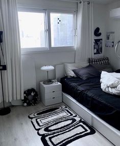 a black and white photo of a bedroom with a bed, window, rug and lamp